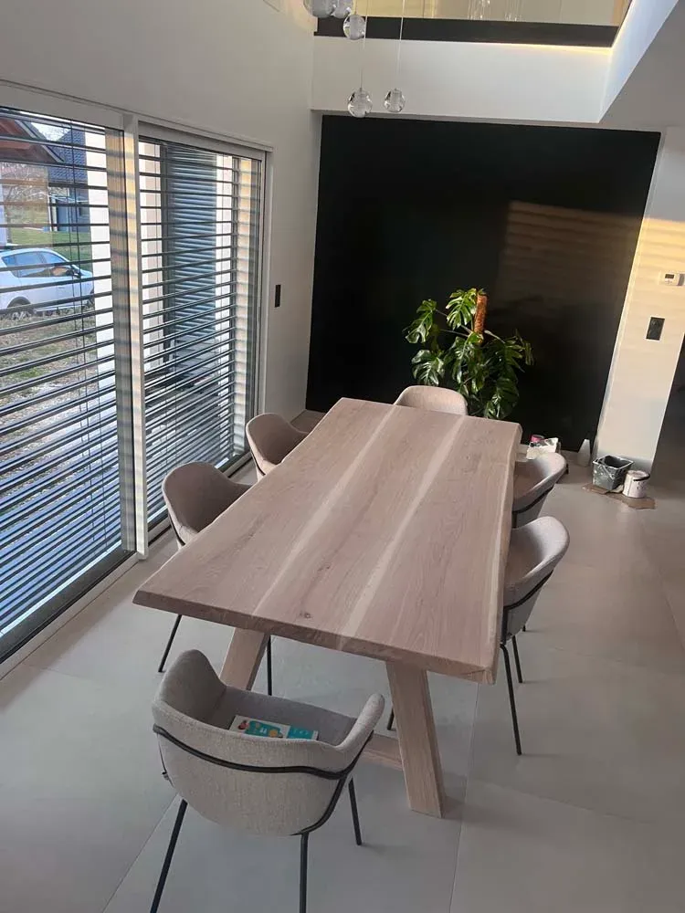 Table à manger en chêne clair et chaises design devant une grande baie
