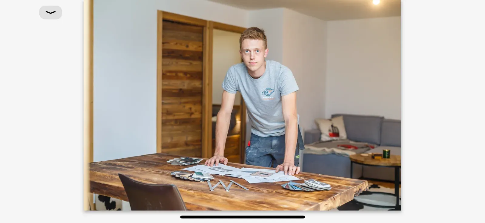 Robin Chalençon étudiant les plans d'un projet sur une table en bois massif dans l'atelier Rob'Art