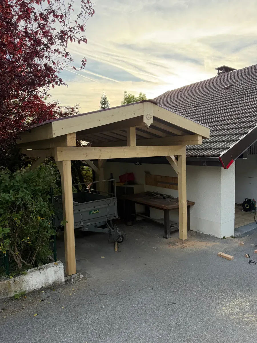 Carport bois sur-mesure adossé à une maison, abritant un établi, réalisé par Rob'Art