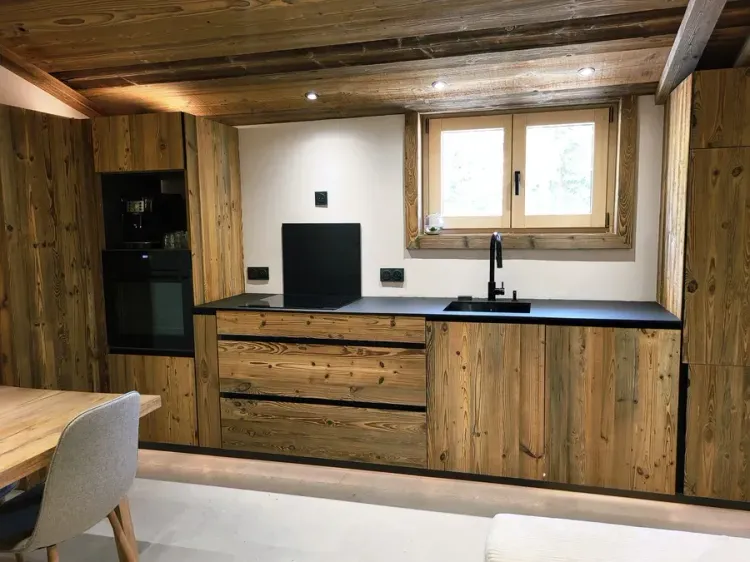 Cuisine sur-mesure en vieux bois avec four encastré et plan de travail noir