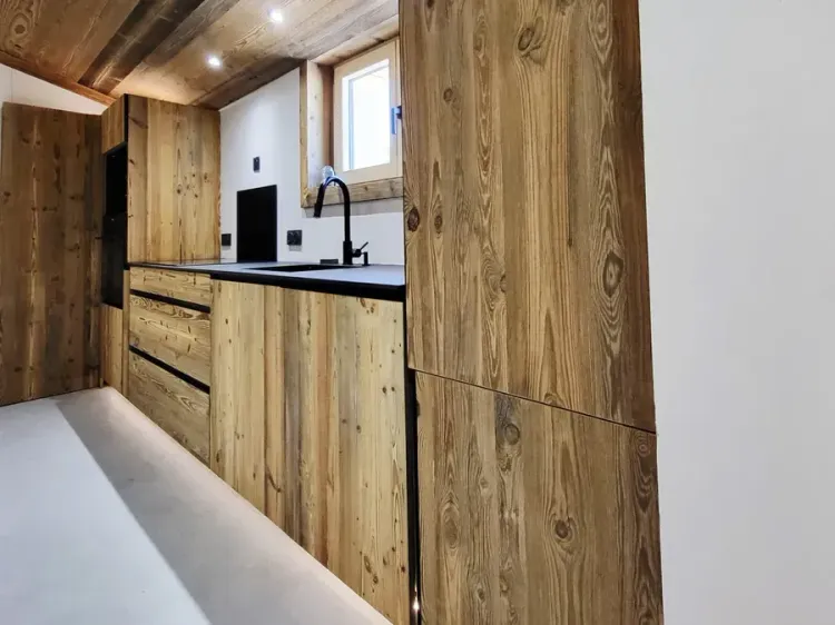 Cuisine aménagée sous rampant avec grande colonne de rangement en vieux bois