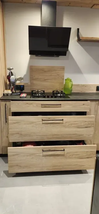 Meuble de cuisine en bois clair avec hotte inclinée et tiroirs sur-mesure