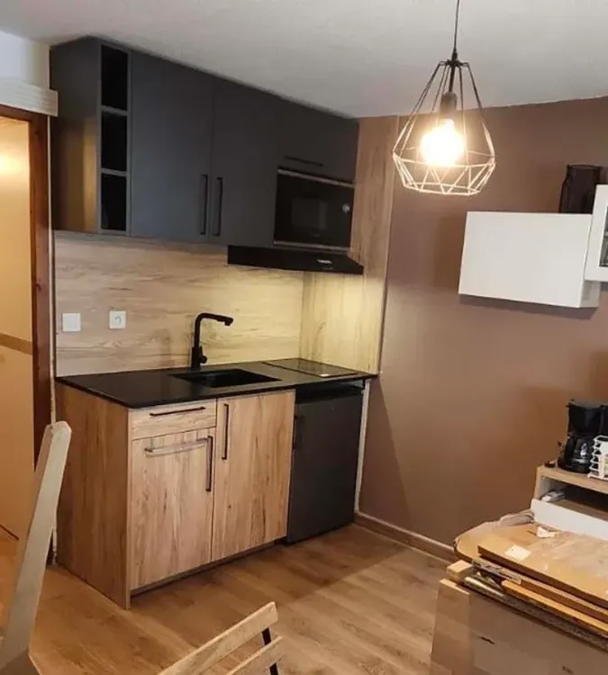 Kitchenette sur-mesure en bois clair avec plan de travail noir et suspension