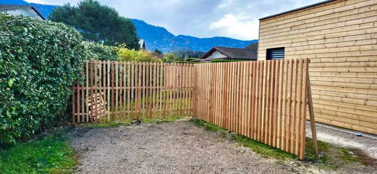 Clôture en bois à lames verticales le long d’un jardin, avec vue sur les montagnes