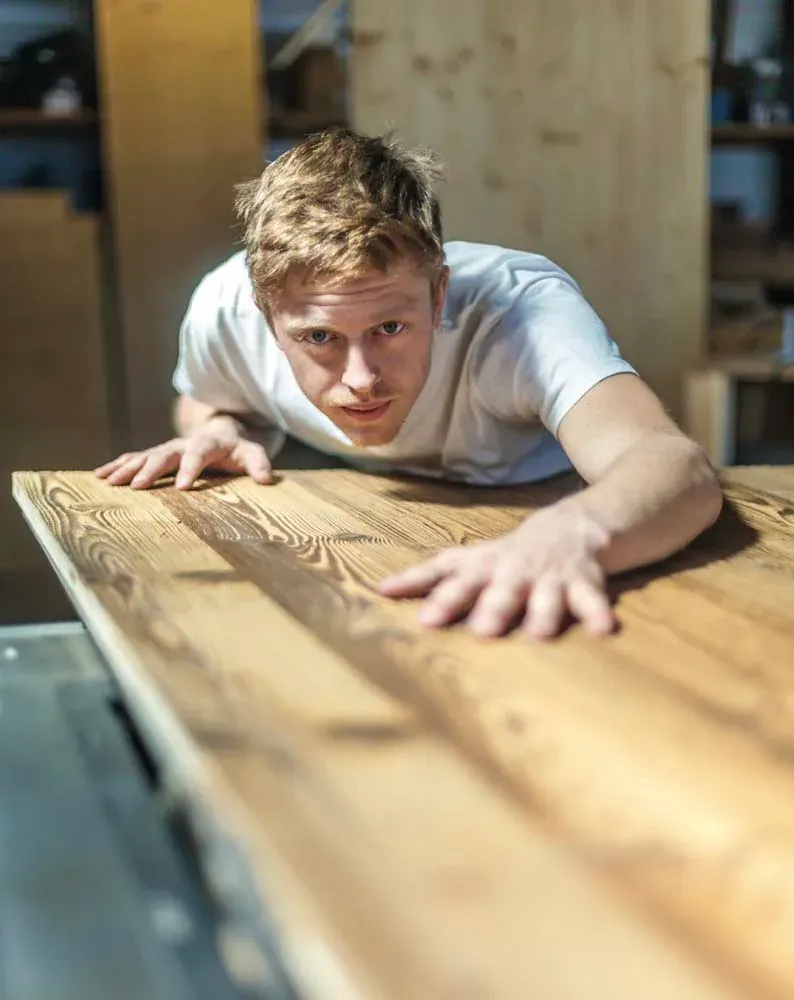 Menuisier Rob'Art contrôlant une planche de bois massif dans l'atelier